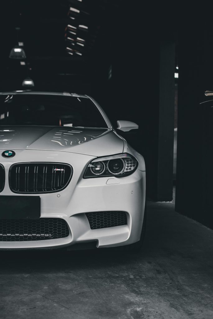 Elegant white luxury car parked indoors, showcasing modern automotive design in a dark setting.
