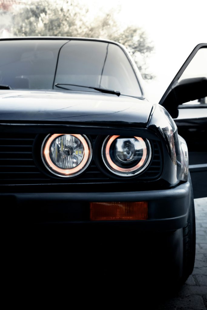Close-up of a vintage BMW E30 car showcasing its iconic circular headlights.