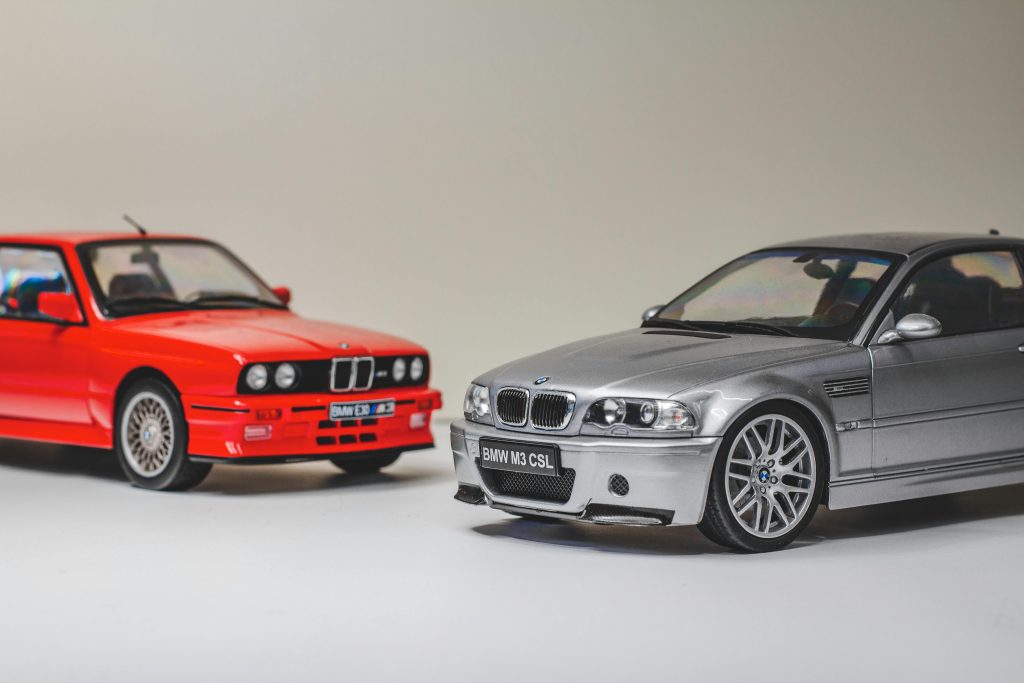Vibrant red and silver BMW model cars on a neutral background, showcasing vintage automotive style.