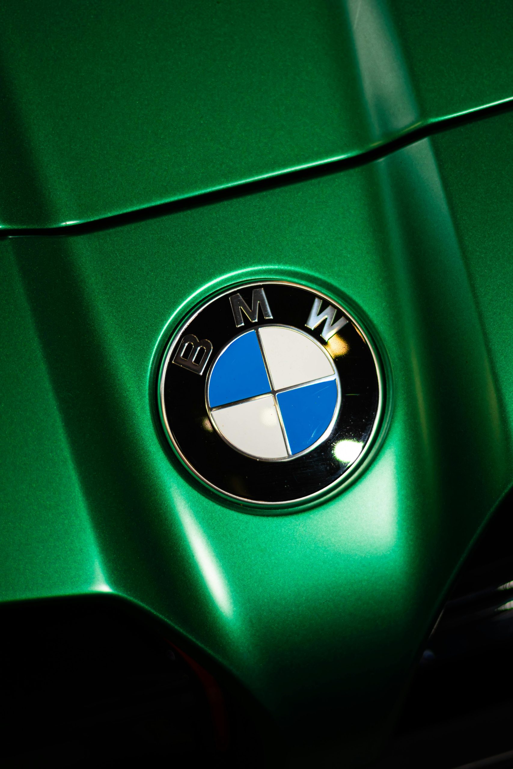 Close-up shot of a BMW logo on a vibrant green hood, capturing automotive elegance.